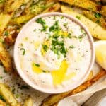 Close up of roasted garlic sauce on a tray of rosemary French fries.