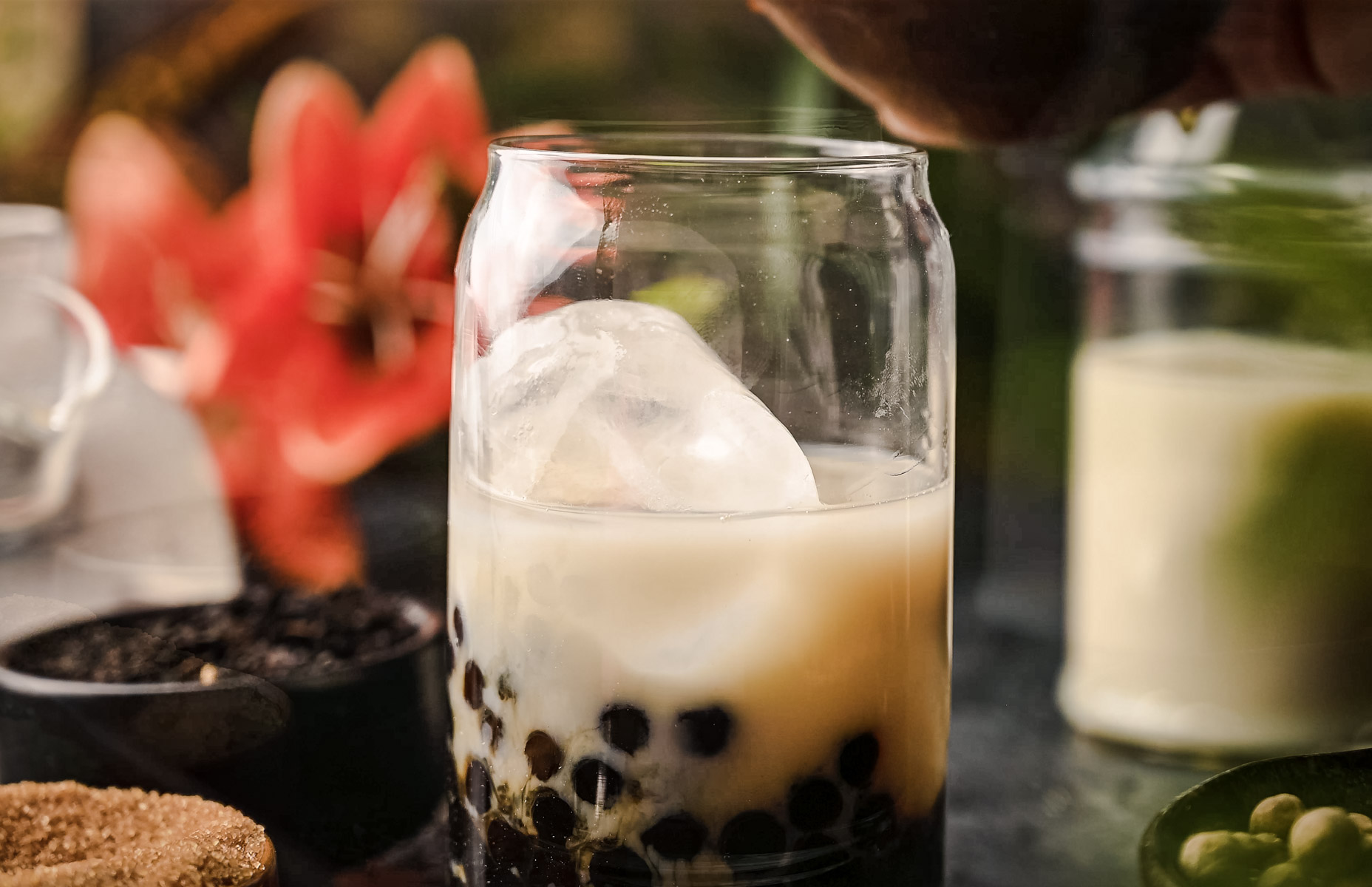 A glass of bubble tea with ice and a flower.
