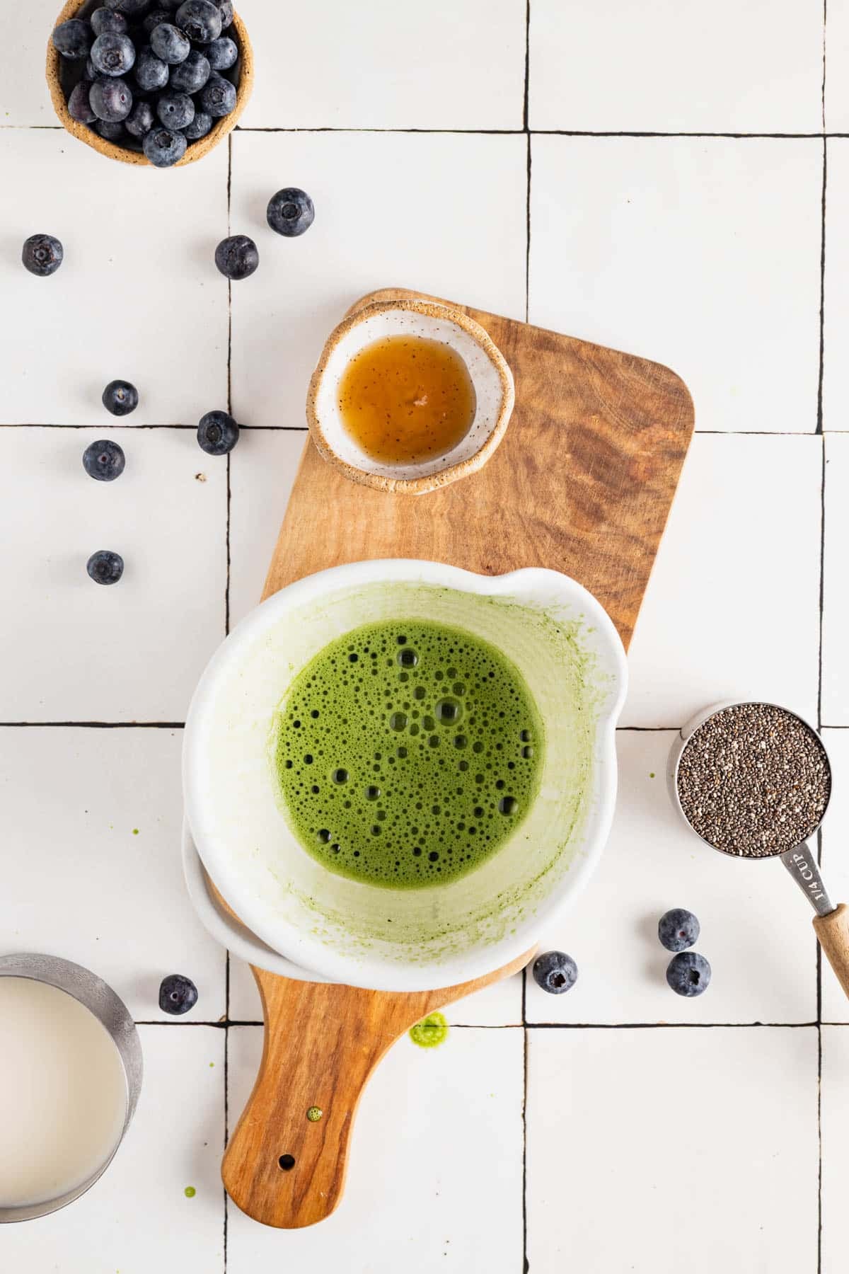 Frothy matcha tea in small white mixing bowl.