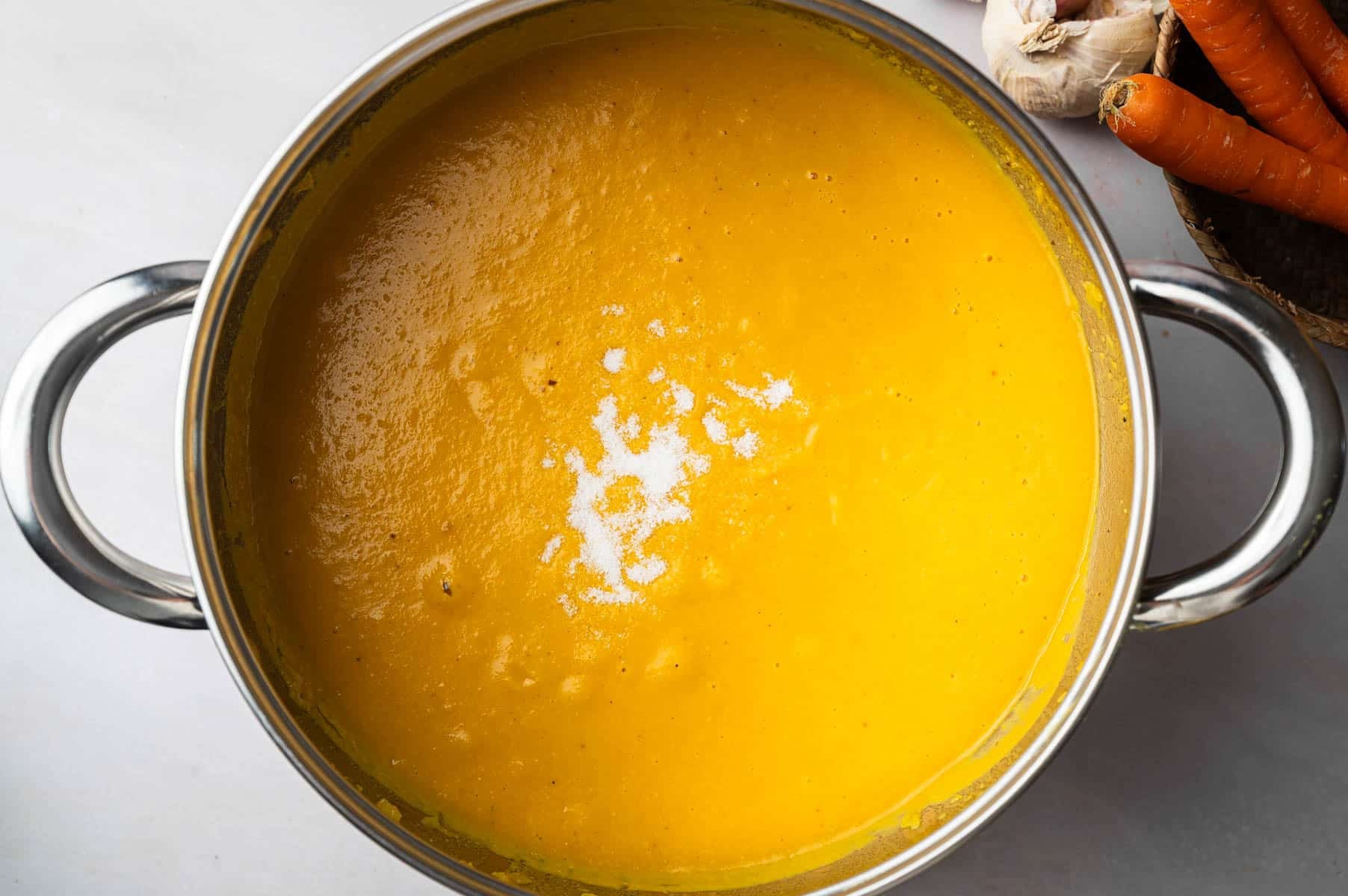 All of the ingredients for carrot and lentil soup in a large stainless steel soup pot on the stove.