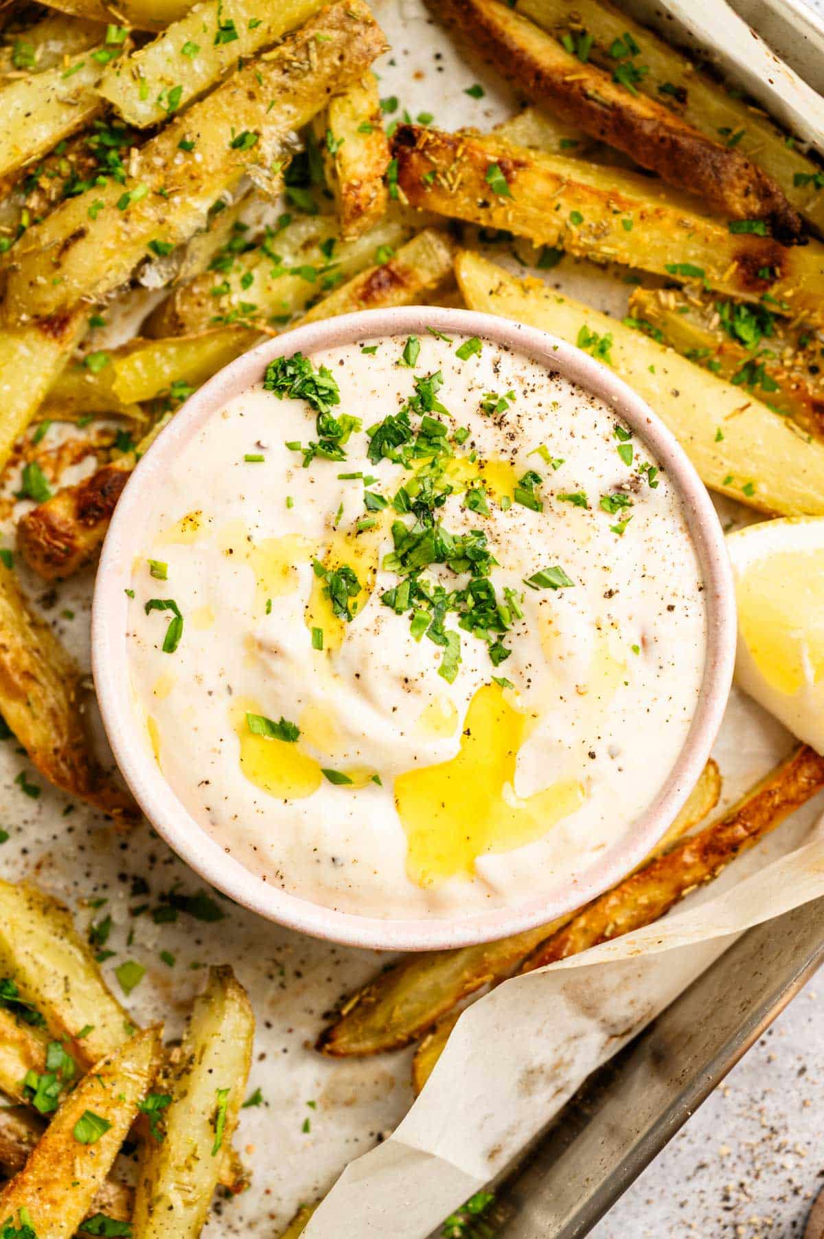 Close up of roasted garlic sauce on a tray of rosemary French fries.