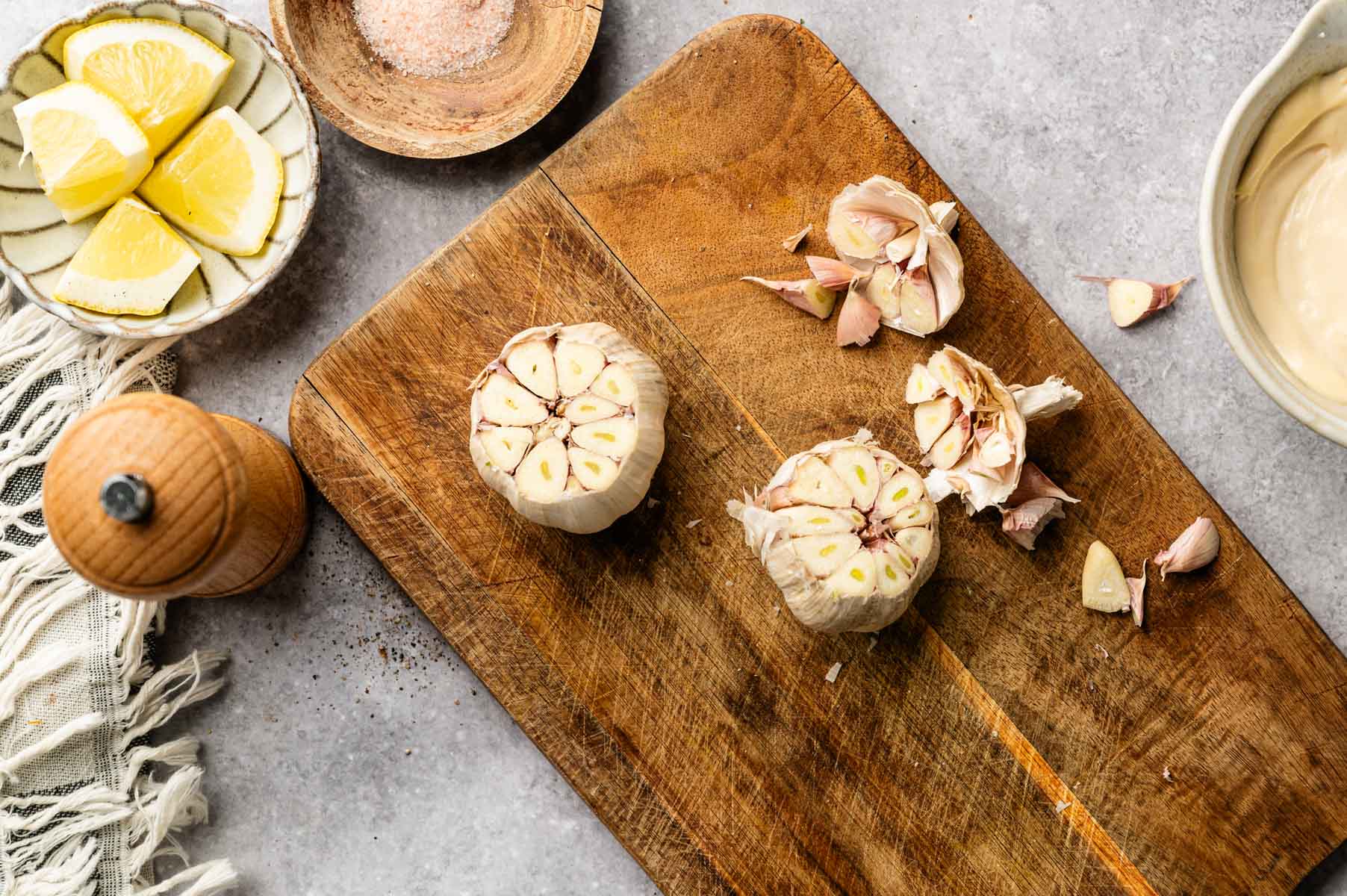 Roasting garlic bulbs by cutting off the top quarter of the bulbs, putting them in aluminum foil and baking them with olive oil.