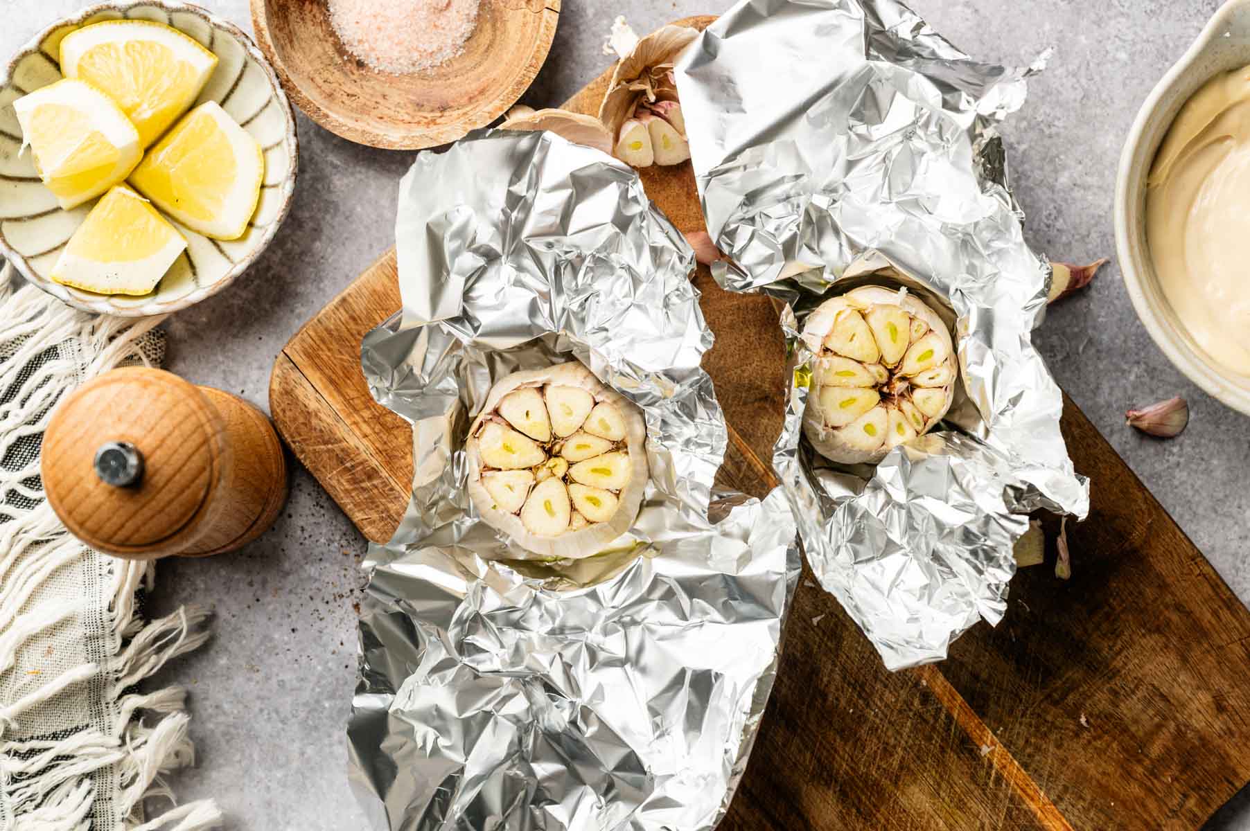 Roasting garlic bulbs by cutting off the top quarter of the bulbs, putting them in aluminum foil and baking them with olive oil.