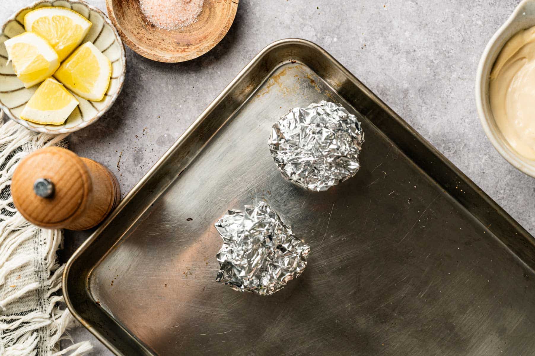Roasting garlic bulbs by cutting off the top quarter of the bulbs, putting them in aluminum foil and baking them with olive oil.