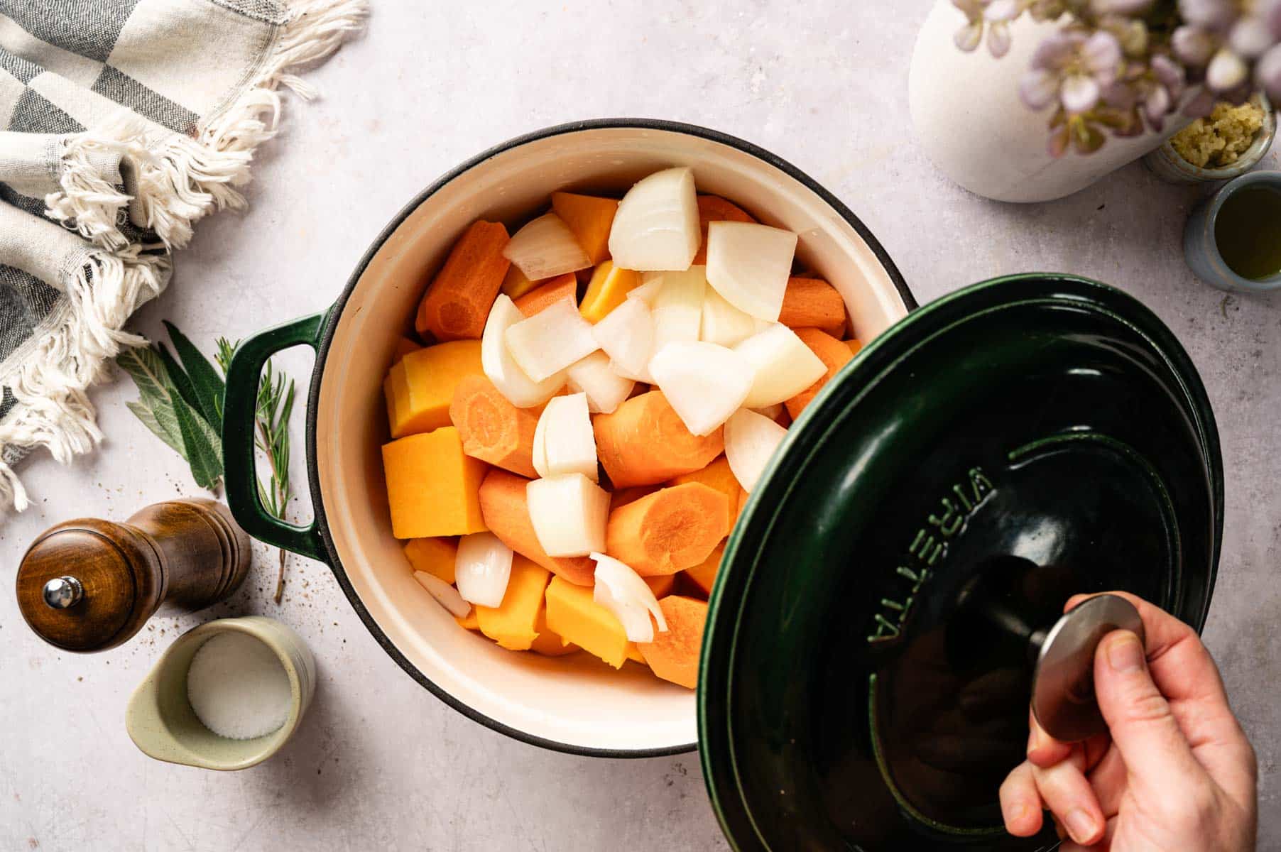 Chopped squash, carrots, onion, and water added to green Dutch oven.