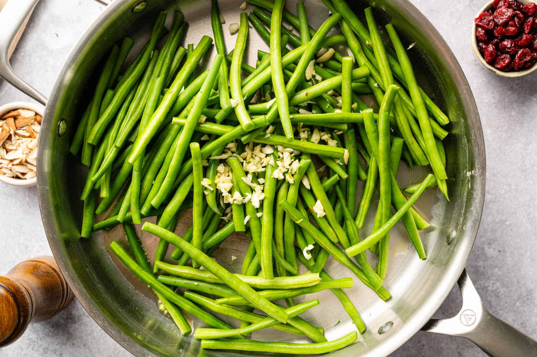 Green beans sautéing in a pan with garlic and spices.