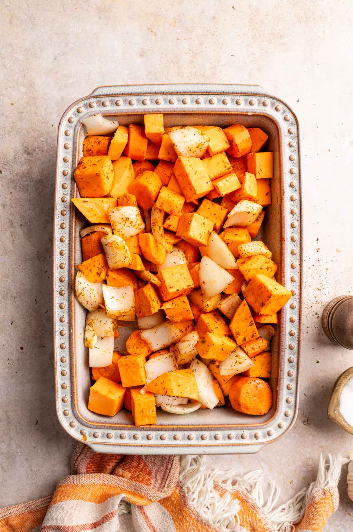 Sweet potatoes, carrots, and onion in a ceramic baking dish.