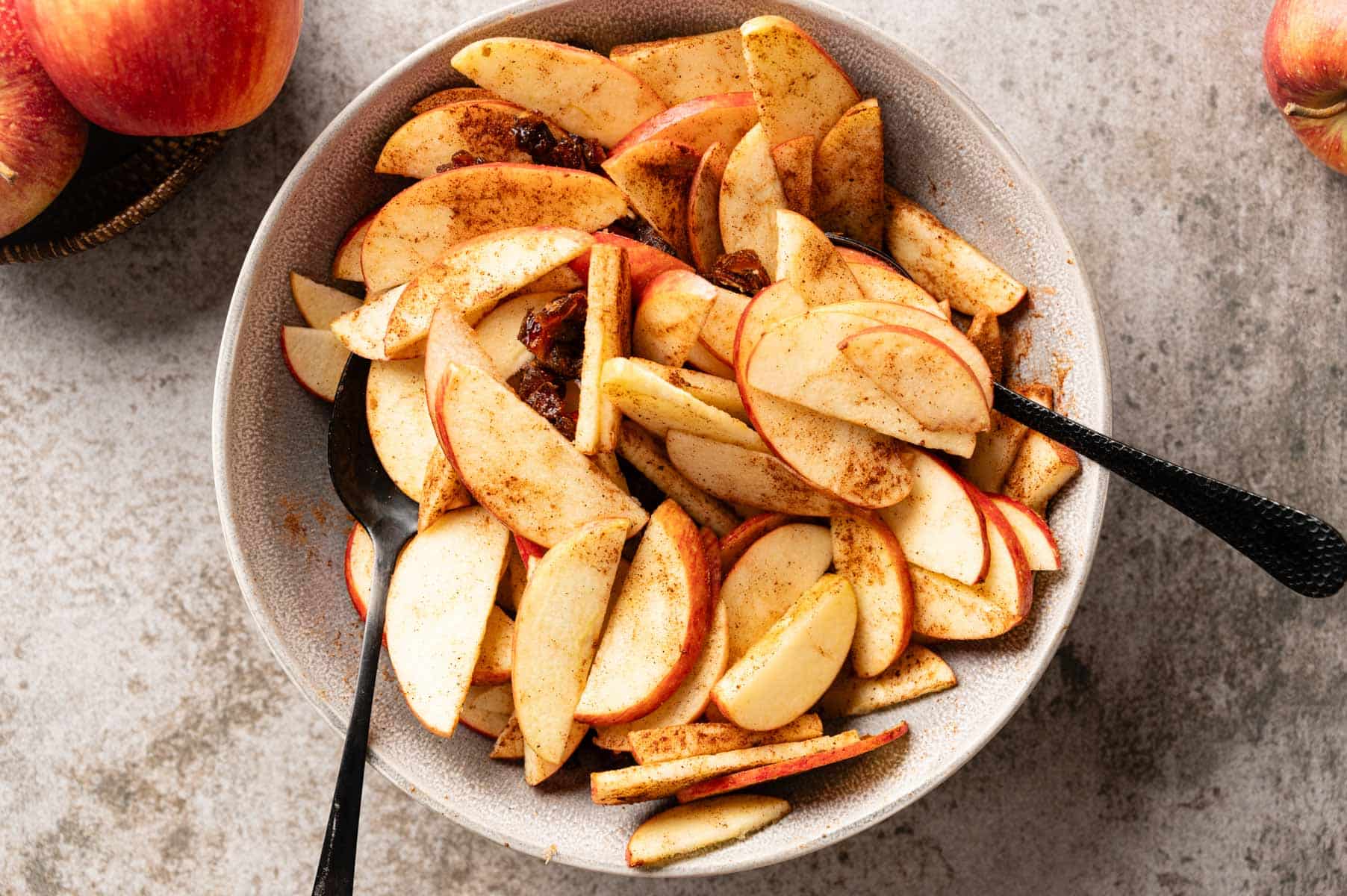Bowl of sliced apples, chopped dates, and spices tossed together.