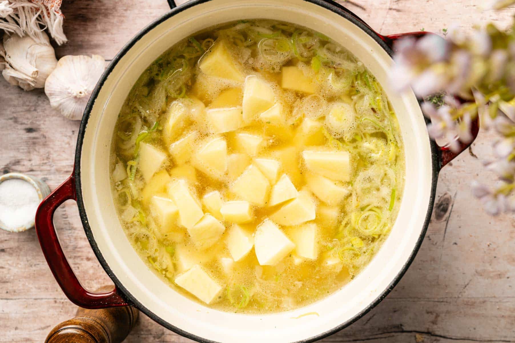 Potatoes added to a Dutch oven with water, onions, and diced leeks.